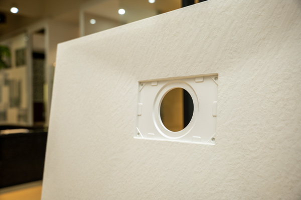 Close-up of white SMC shower tray surface with molded rectangular frame around the circular drain opening