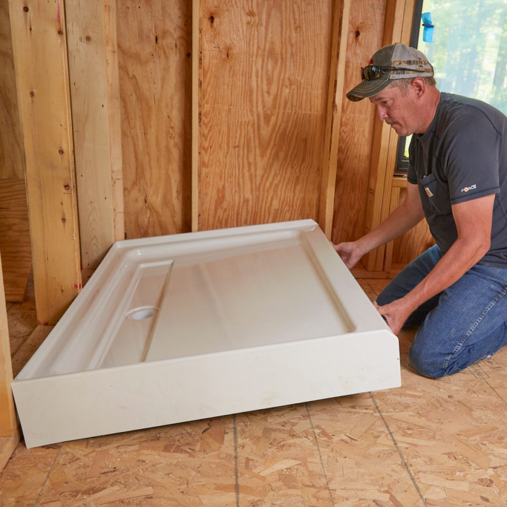 a man installing the shower tray