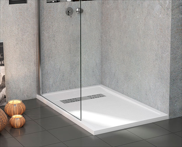 Frameless glass shower panel with white low-profile tray and linear channel drain on dark grey tiles, woven basket decor