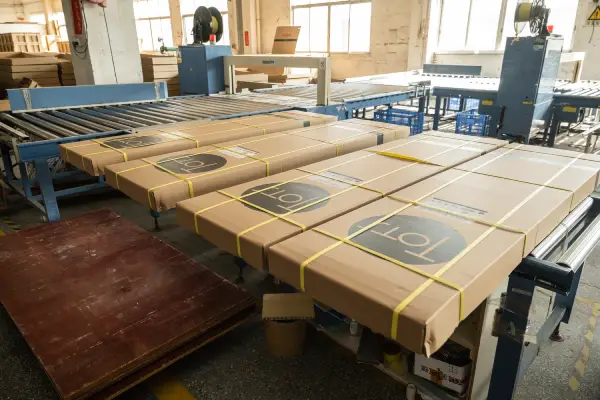 Kraft paper wrapped shower wall panel packages with yellow straps on conveyors ready for shipping in the KJbath factory