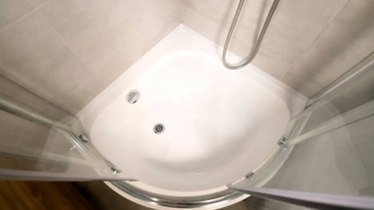 Top-down view of white quadrant corner shower tray with chrome framed glass doors and handheld shower hose