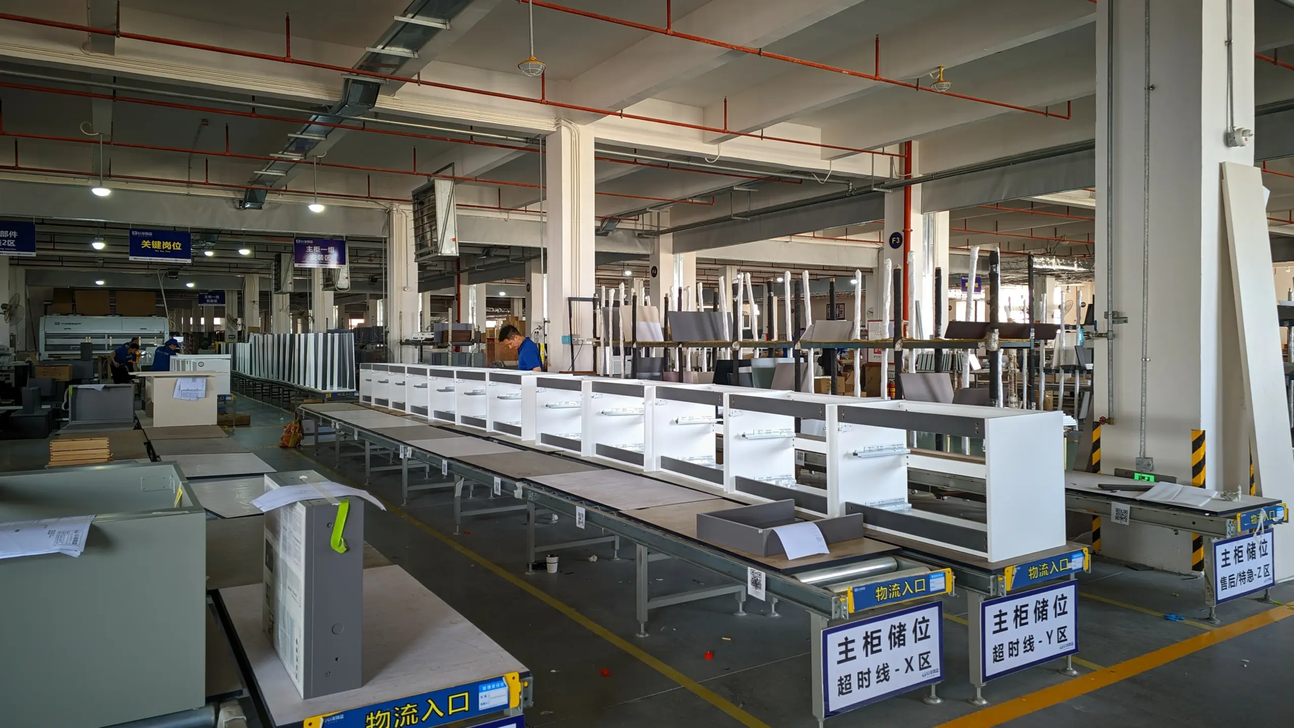 Workers in blue uniforms assembling and inspecting products along an organized conveyor production line in the KJbath workshop