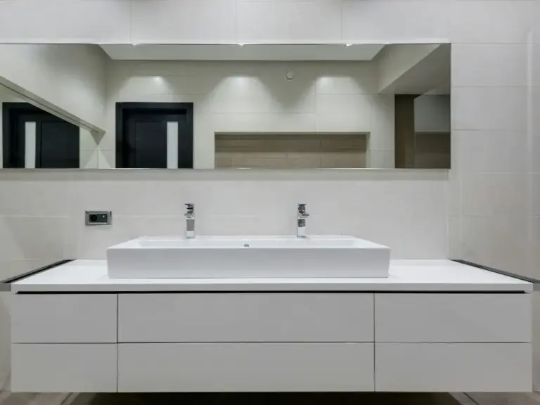 White floating bathroom vanity with vessel sink, chrome faucets and six handleless light gray drawers under a mirror